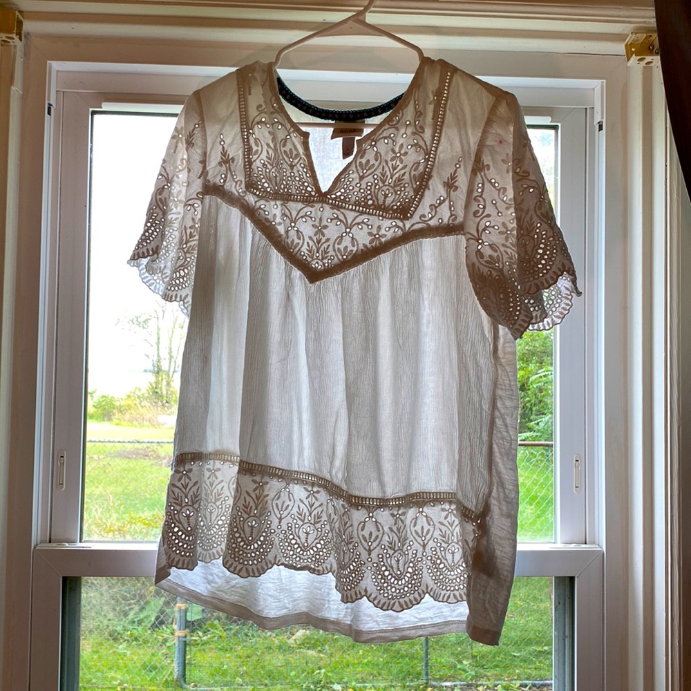 It’s a large white top that’s made from cotton and has a pretty design.